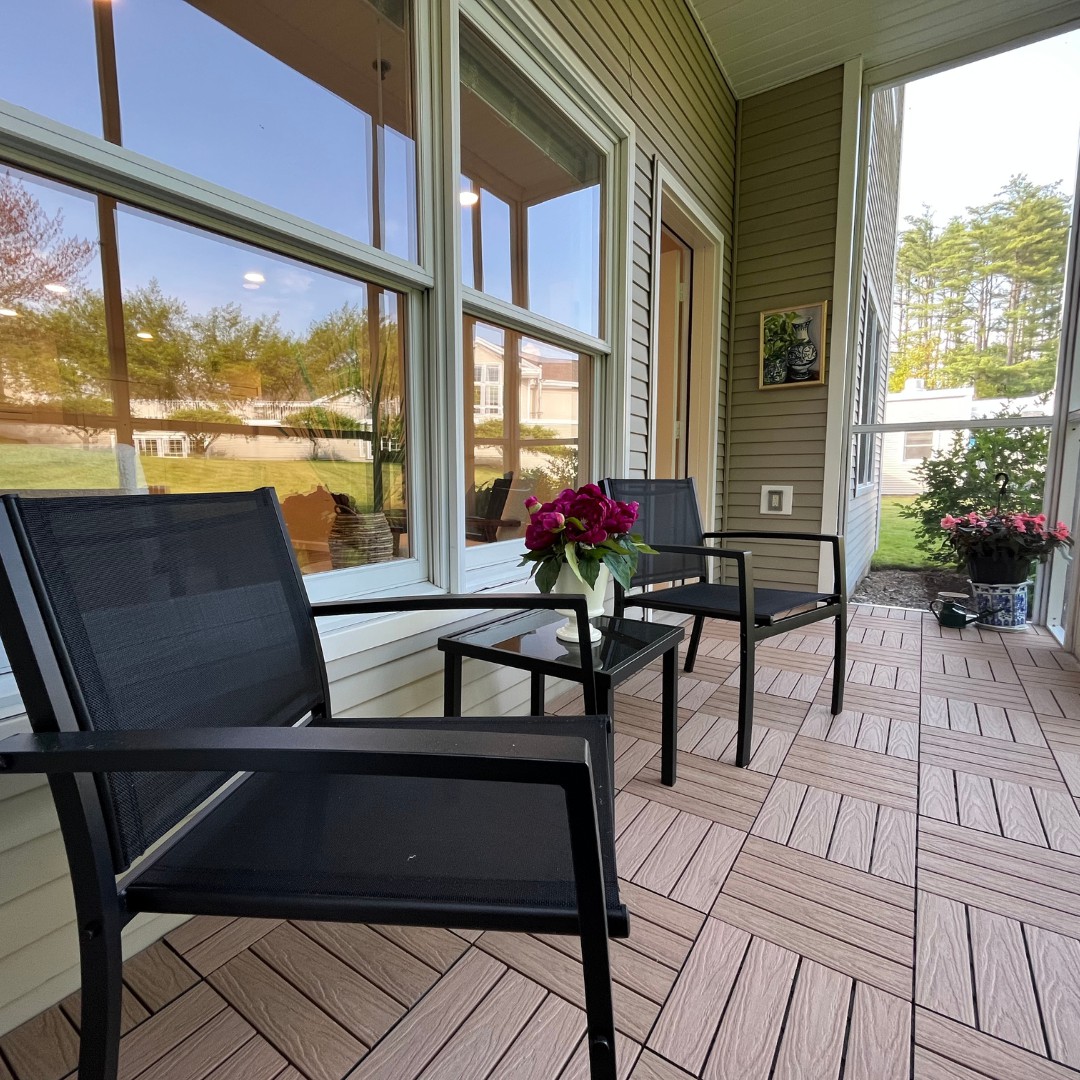 A cozy porch with two chairs, a small table, and flowers, perfect for relaxation.