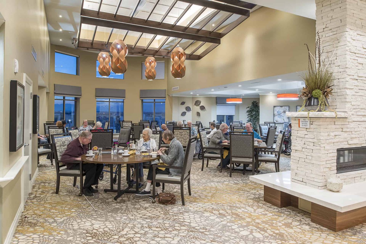 A spacious dining area with seniors enjoying a meal at various tables.