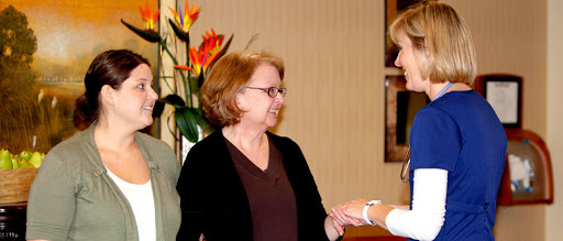 Two people engaged in a friendly conversation indoors, surrounded by decorative flowers.