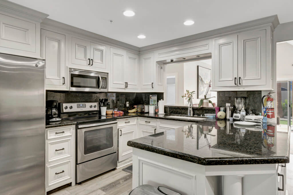 A modern kitchen featuring stainless steel appliances and white cabinets with granite countertops.