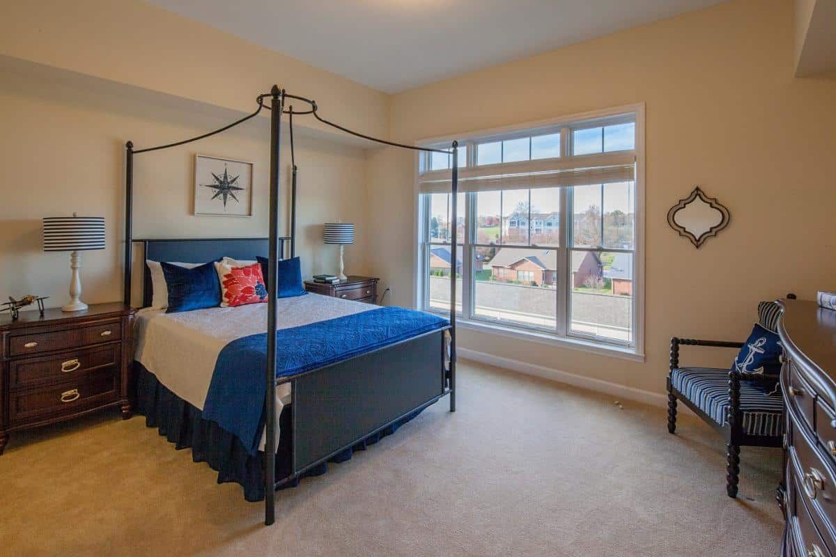 A modern bedroom with a four-poster bed, large windows, and stylish decor.