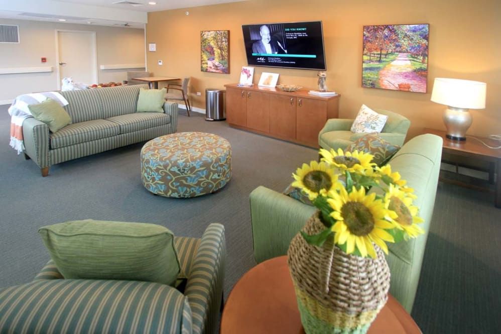 A cozy living room with green sofas, a central coffee table, and sunflowers as decor.