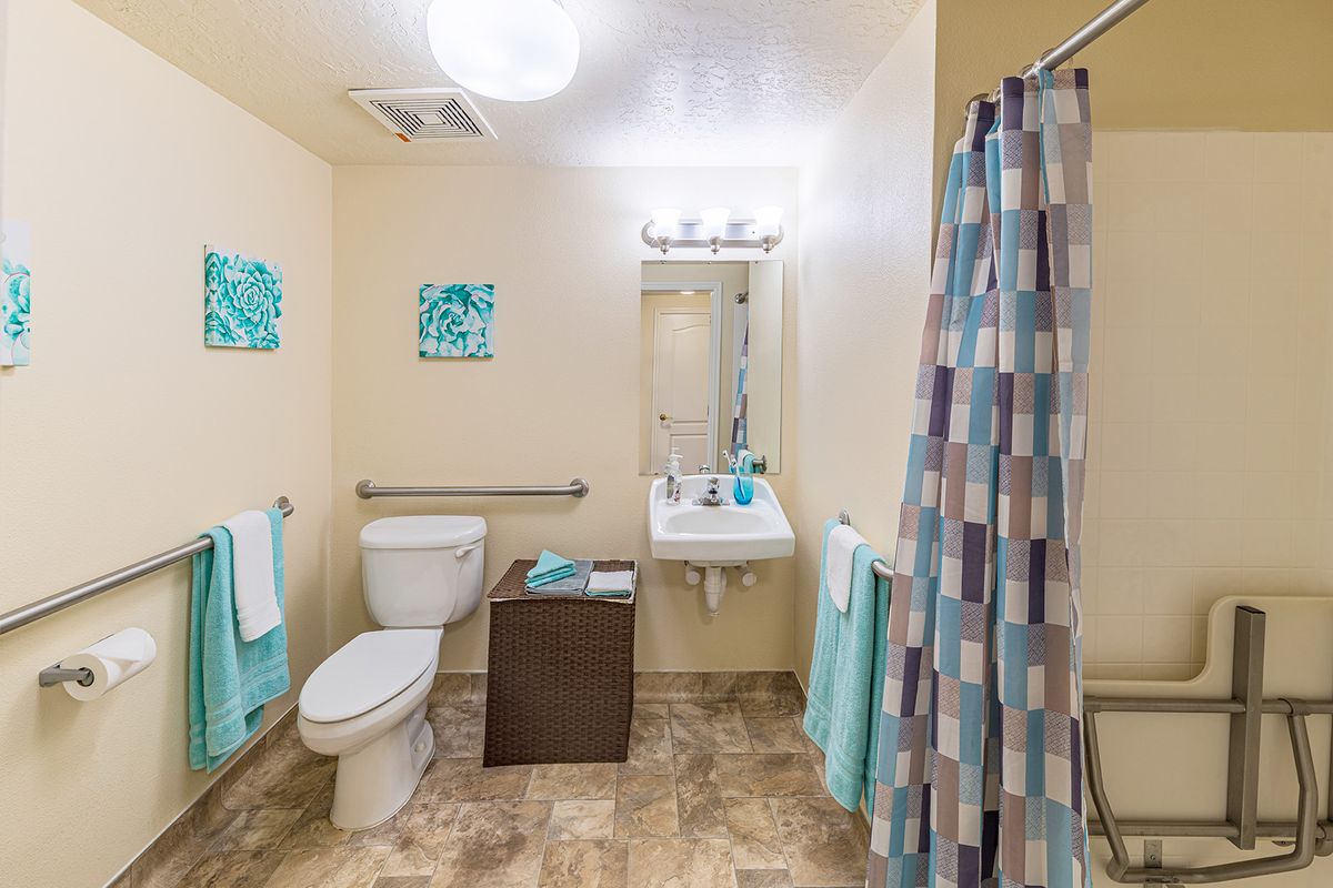 A well-organized bathroom with a toilet, sink, and shower curtain in soft blue tones.