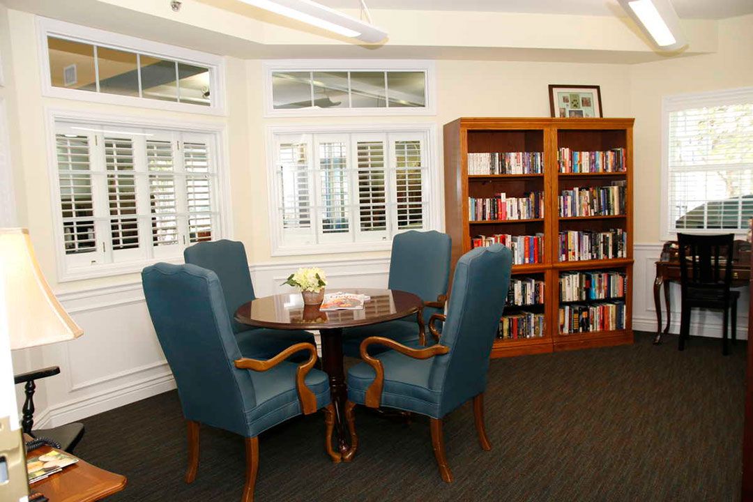 A cozy library reading area with a table and chairs surrounded by bookshelves.