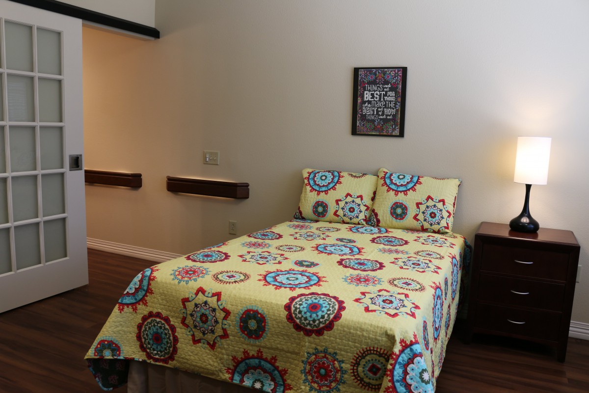 A cozy bedroom with a colorful patterned bedspread.