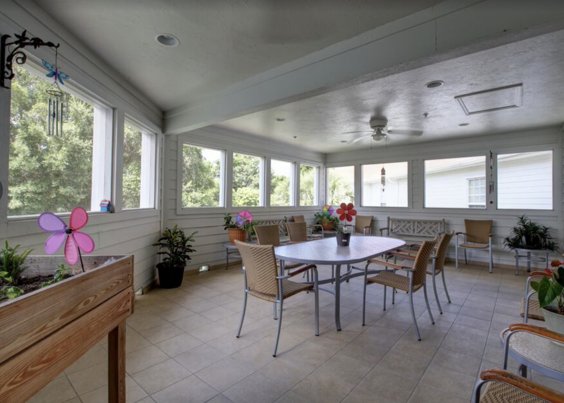 A sunroom with a dining table, surrounded by windows and filled with natural light.