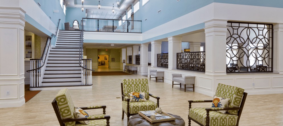A spacious and well-lit lobby area with stylish furniture and a staircase.