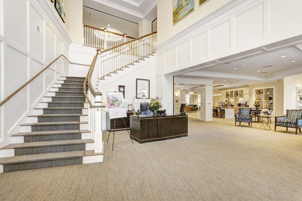 A spacious and bright lobby area with a grand staircase and reception desk.