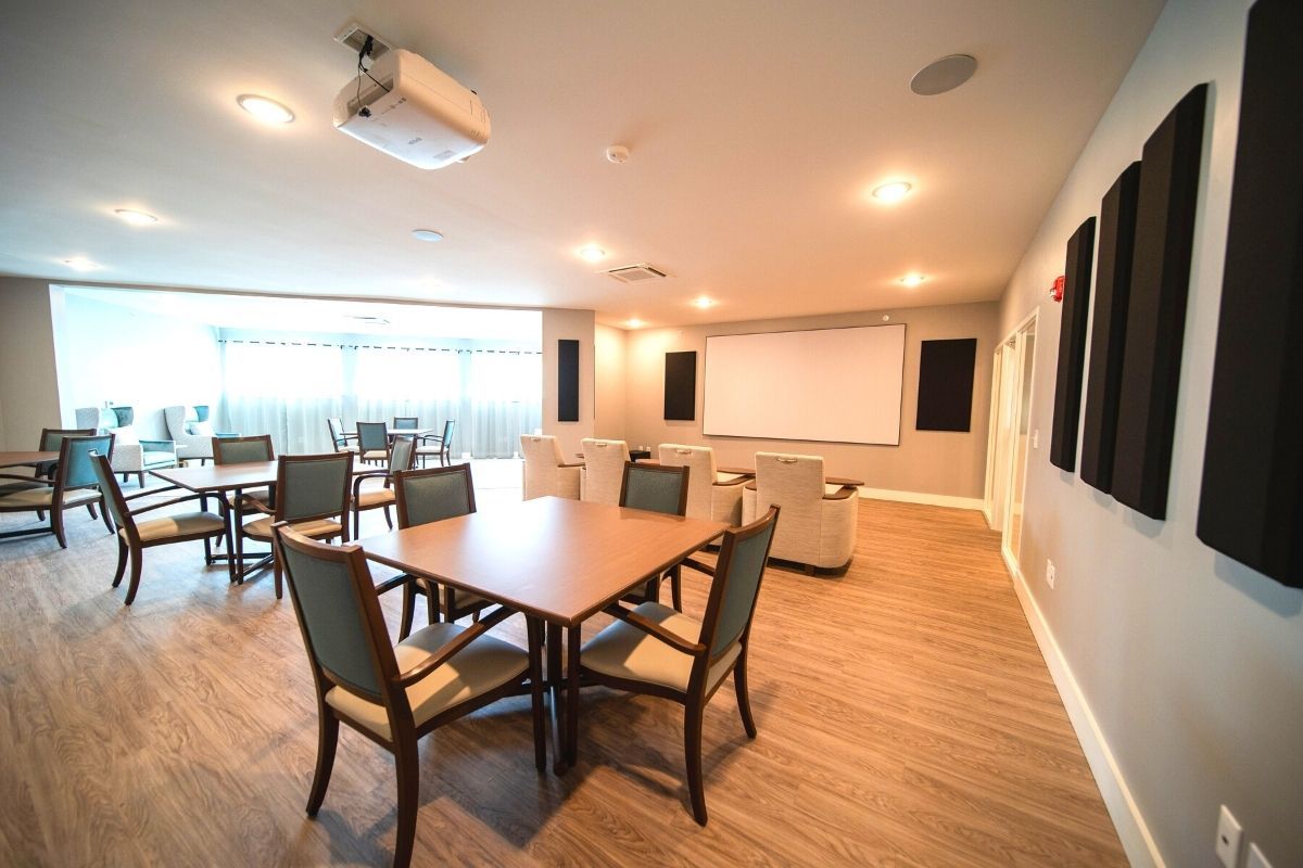 A modern conference room equipped with tables, chairs, a projector, and a large screen.