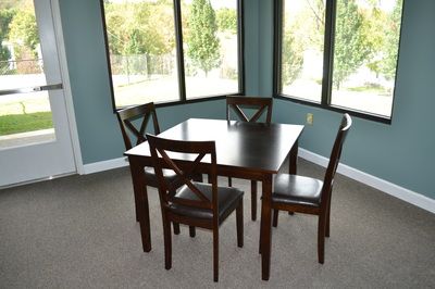 A dining area with a dark wooden table and four matching chairs near large windows that provide natural light.