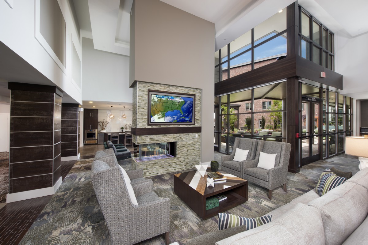A spacious and modern living room with large windows, a central fireplace, and contemporary furnishings.