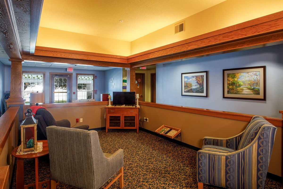 A cozy lobby area with comfortable seating, framed art on the walls, and a television.
