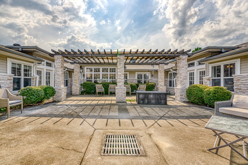 An inviting outdoor patio area with a pergola and stone columns under a cloudy sky.