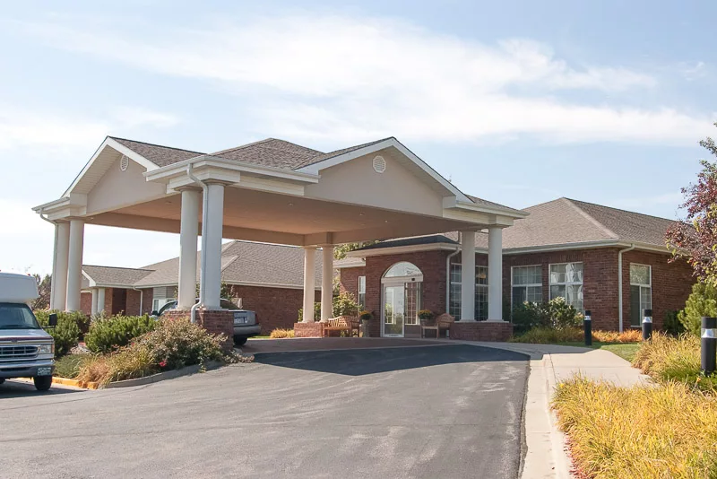 A large building with a driveway and covered entrance featuring columns.