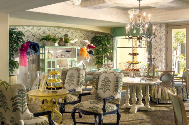 A cozy and elegant vintage-style interior featuring a floral-patterned decor, ornate furniture, and a chandelier.