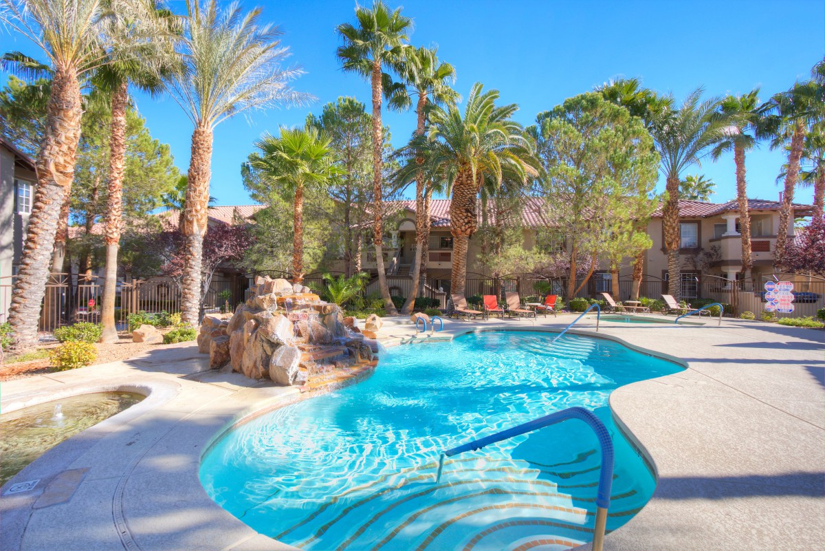 A tranquil outdoor pool area surrounded by palm trees, perfect for a sunny vacation retreat.
