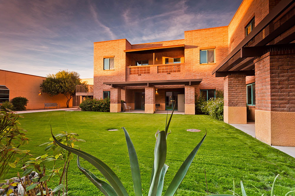 A modern house with a spacious green lawn at sunset.