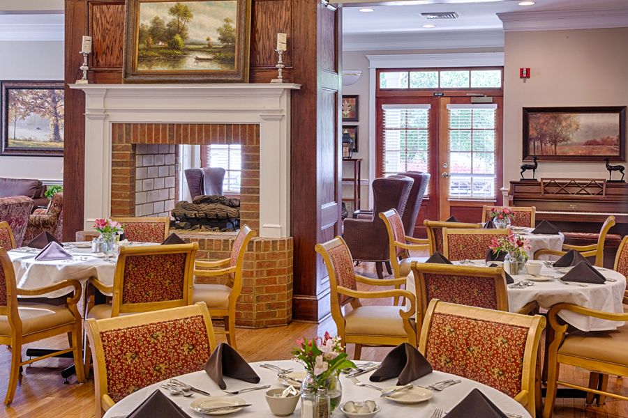 A cozy and elegantly decorated dining room with neatly arranged tables and chairs, featuring a fireplace centerpiece.