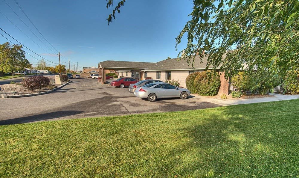 A small building with a parking lot and several parked cars on a sunny day.