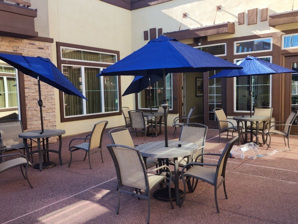 An outdoor patio with tables and blue umbrellas arranged for dining.
