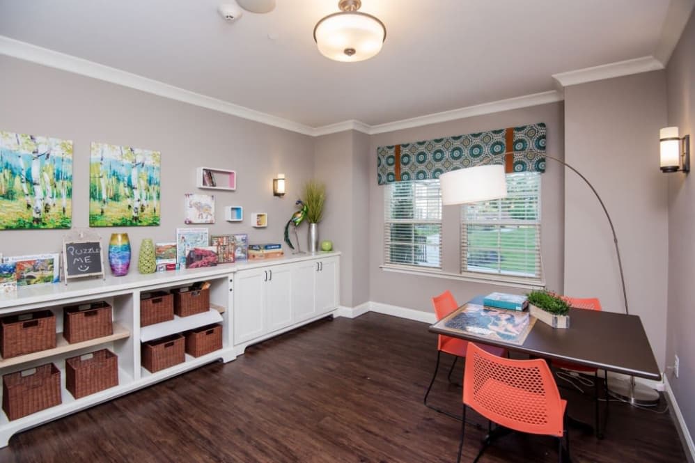 A colorful classroom setup with art supplies and storage, featuring bright chairs and a large window.