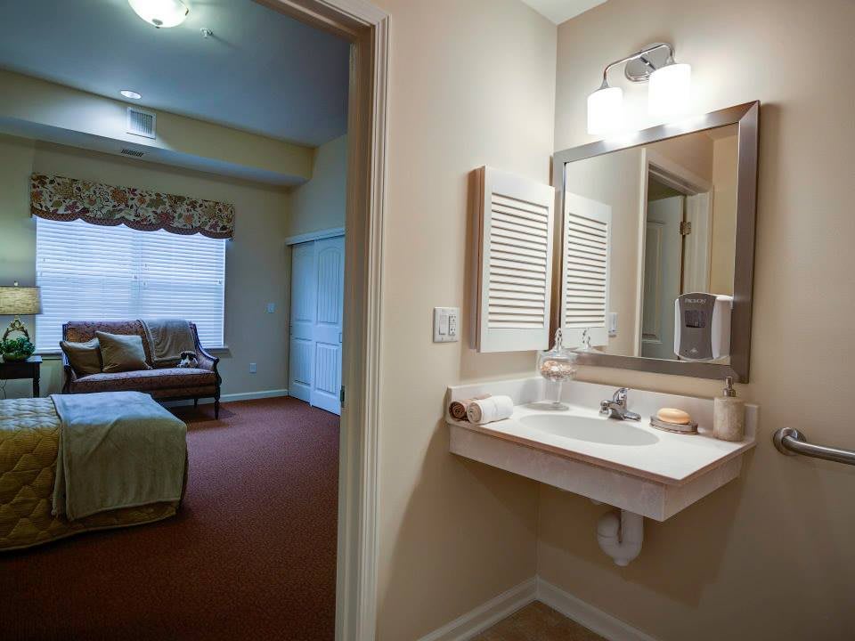 A cozy residential bathroom with a view of an adjacent bedroom.