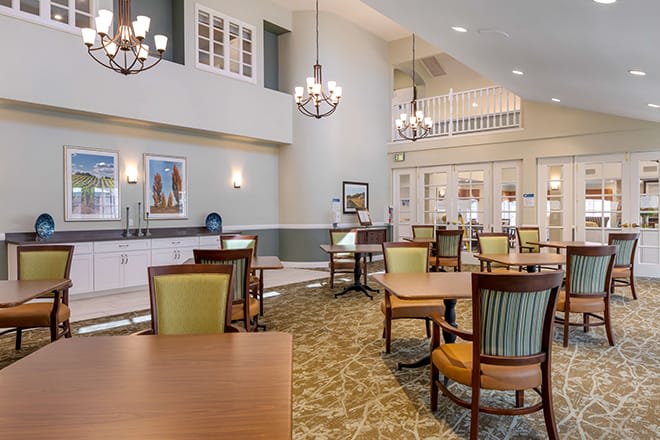 A well-lit dining area with elegant chandeliers, comfortable seating, and tasteful decor.