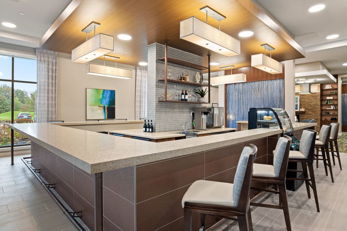 A modern bar interior featuring a sleek design with seating, contemporary lighting, and a minimalist countertop.