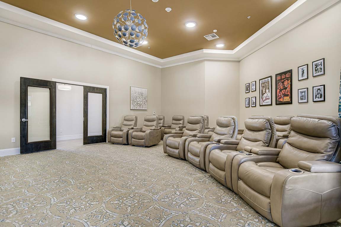 A modern home theater room featuring a row of comfortable recliner chairs and minimalist decor.