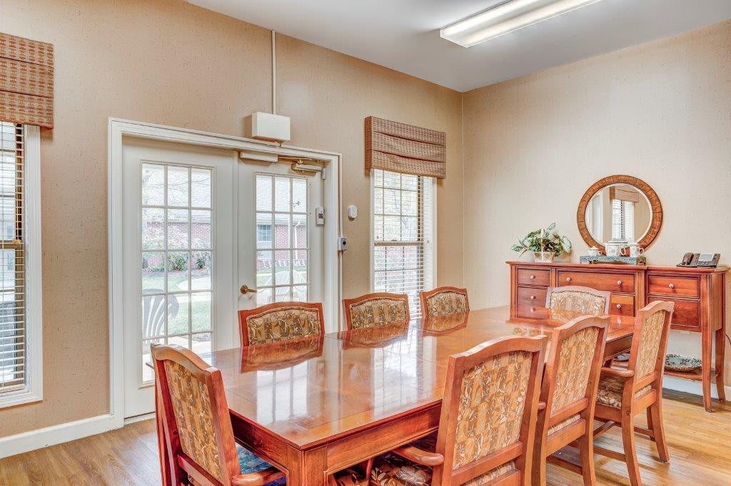 A well-lit dining room featuring a large wooden table and chairs with windows allowing natural light in.
