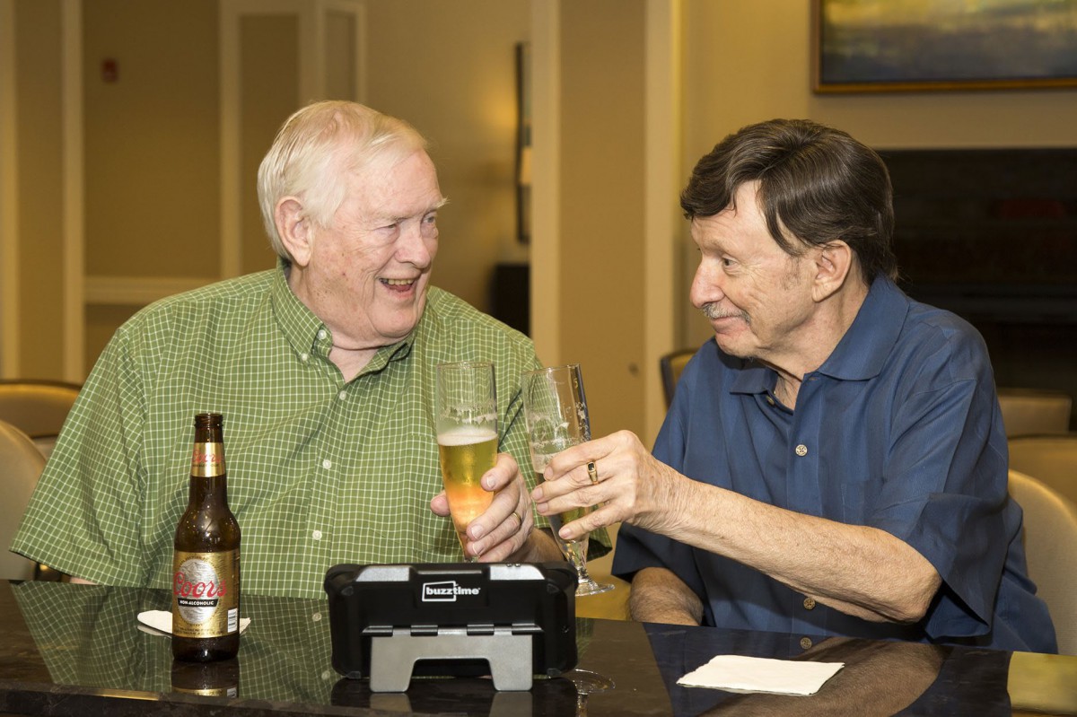 Two men enjoying a drink together and laughing.