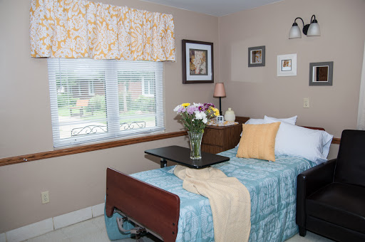 A cozy bedroom featuring a comfortable bed, fresh flowers, and a serene view through the window.