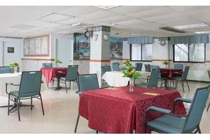 An empty dining area with tables covered in red tablecloths and neatly arranged chairs.