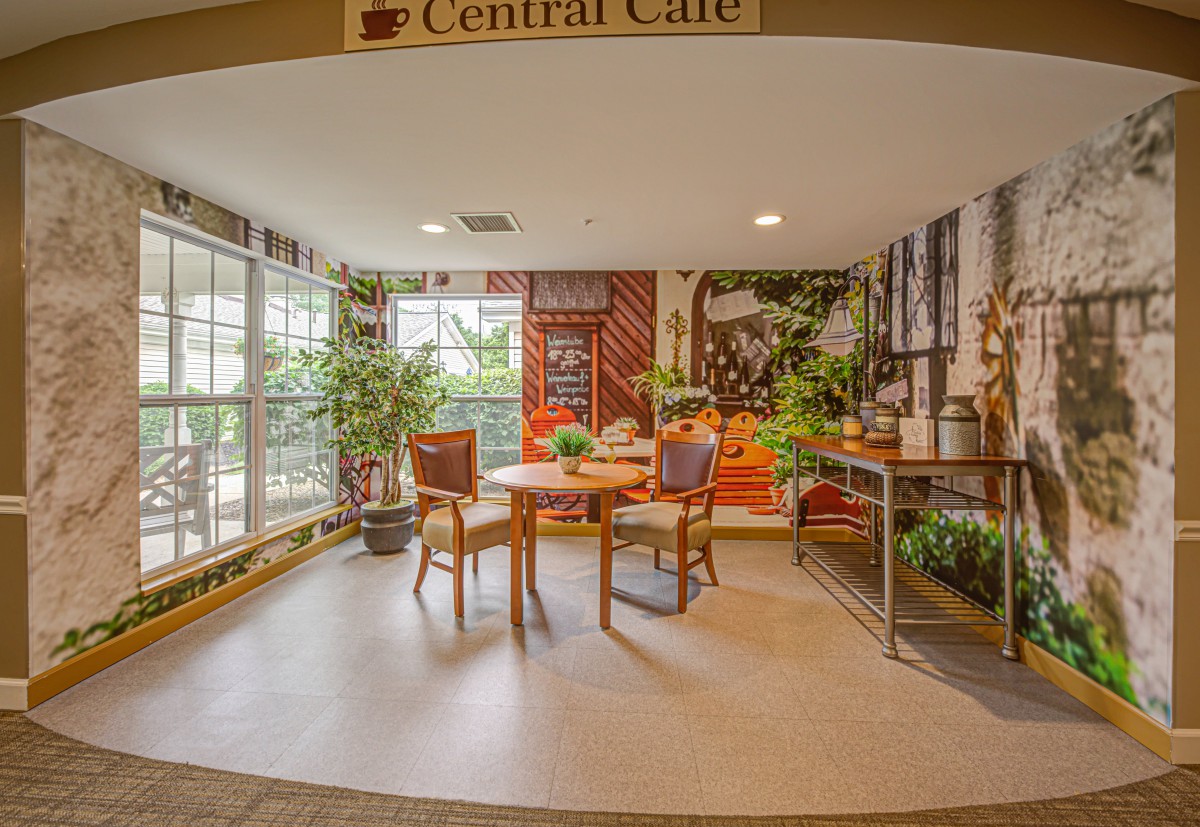 A cozy cafe interior with tables, chairs, and lush green plants.