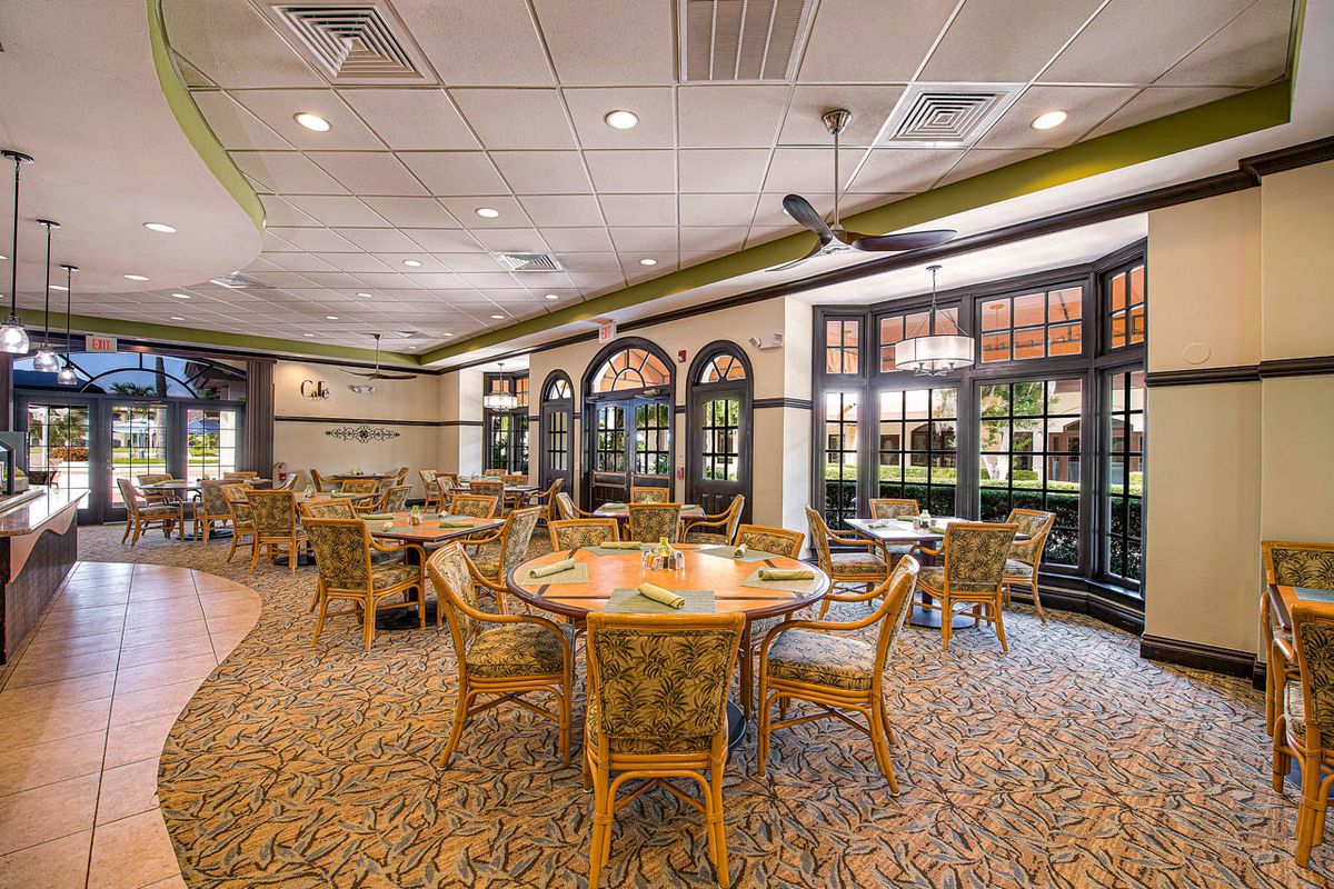 A spacious restaurant interior with wicker chairs and tables set in a well-lit dining area.