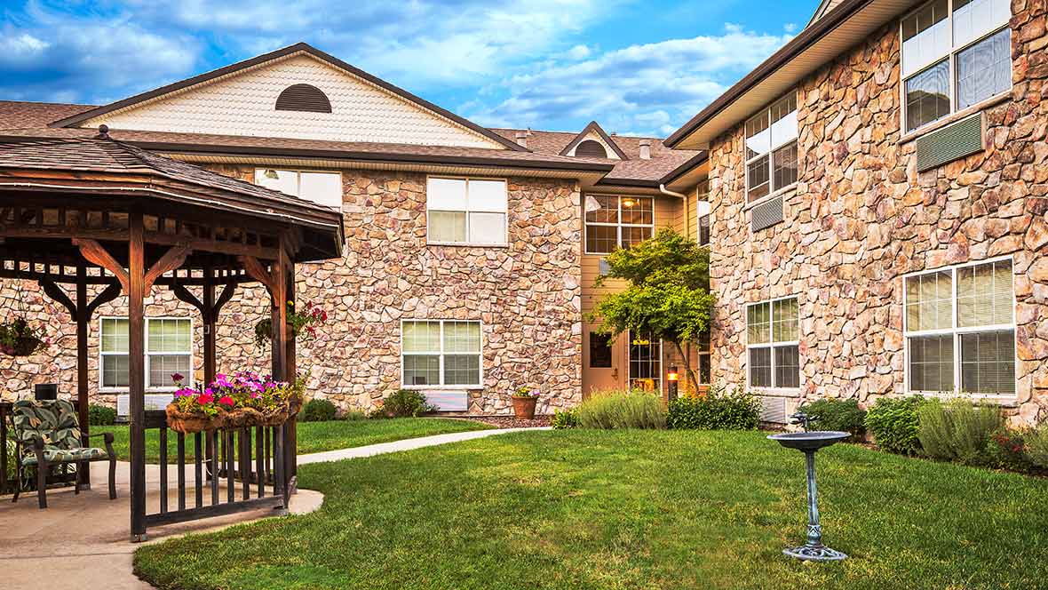 A residential building with a brick exterior, featuring a landscaped courtyard and a wooden gazebo.
