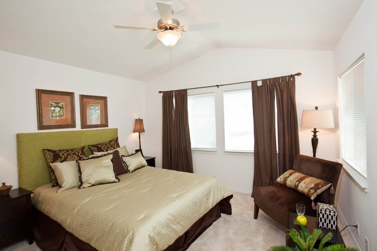 A cozy bedroom featuring a large bed with green accents, brown curtains, and tasteful decor.