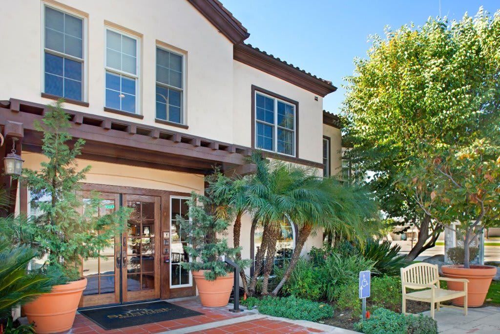 A modern residential building with a landscaped entrance and large windows.
