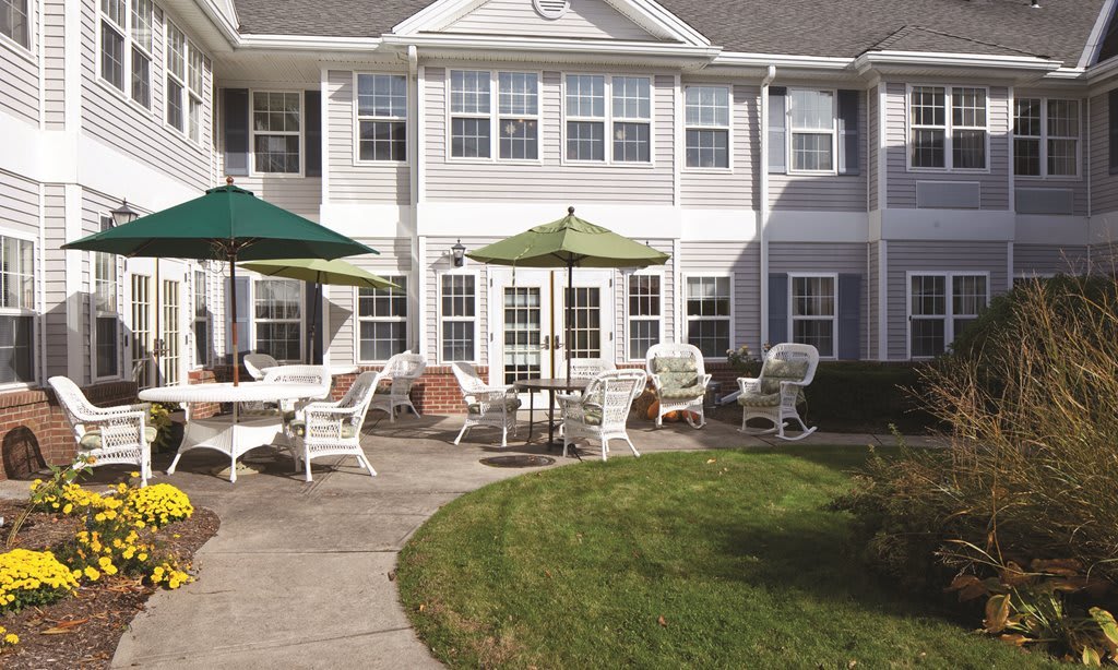 A residential patio area with chairs and umbrellas on a sunny day.
