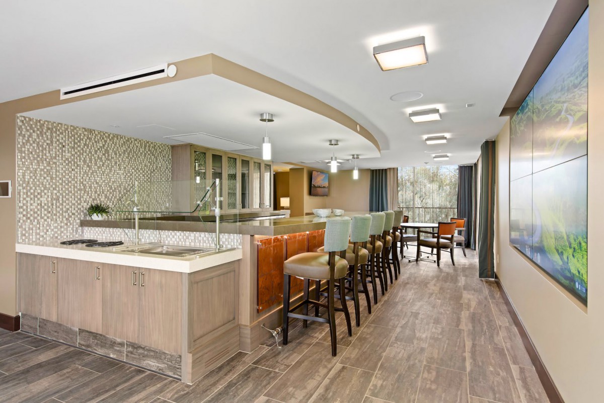 A modern kitchen with an open layout featuring bar stools and stylish lighting.