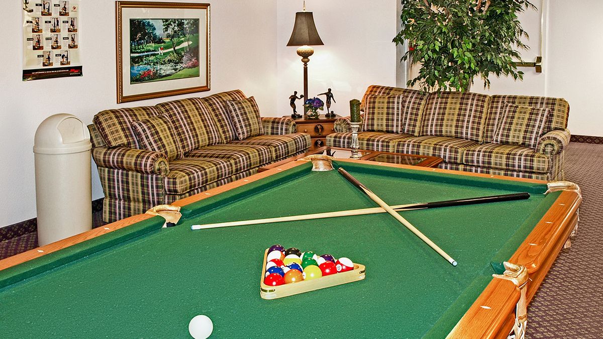 A cozy living room featuring a pool table with cues, surrounded by sofas and stylish decor.