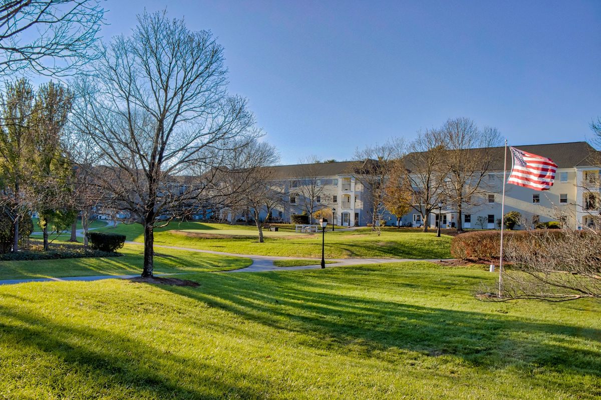 A scenic view of a campus with a large lawn and trees under a clear blue sky.