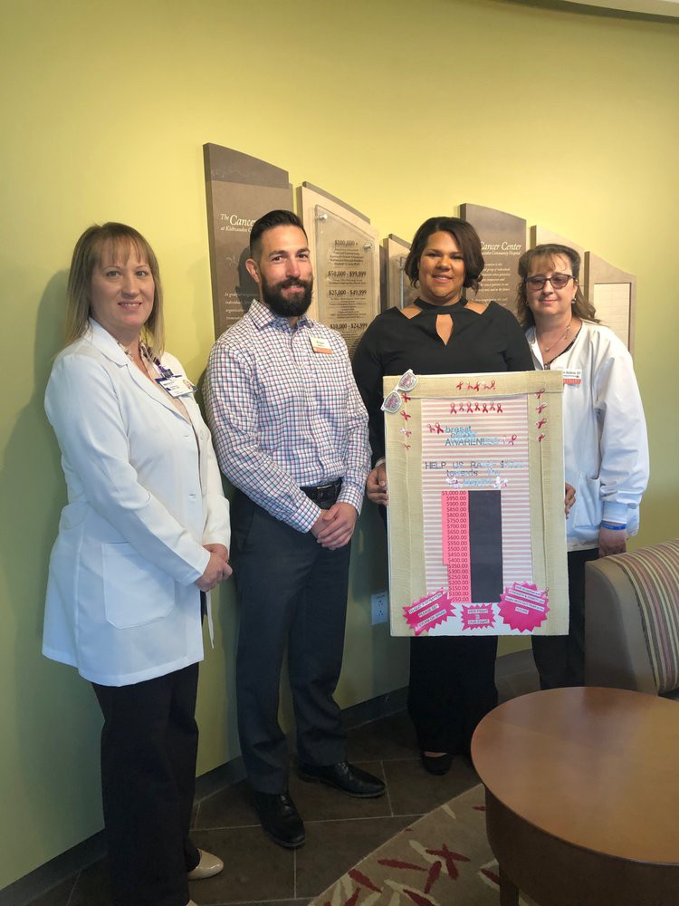 A group of healthcare professionals posing with a chart in a hospital setting.