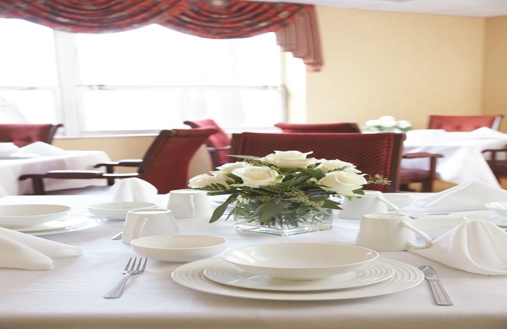 An elegant dining table set with white plates and a floral centerpiece.