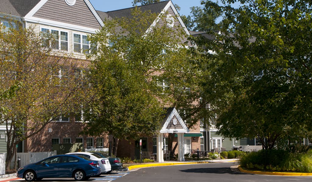A residential building with parked cars and surrounding trees.