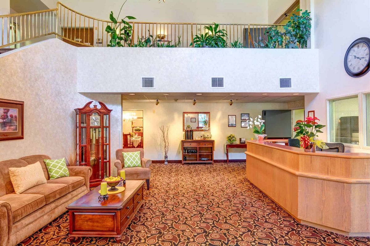 A hotel lobby featuring a reception desk, sofas, and decorative elements.