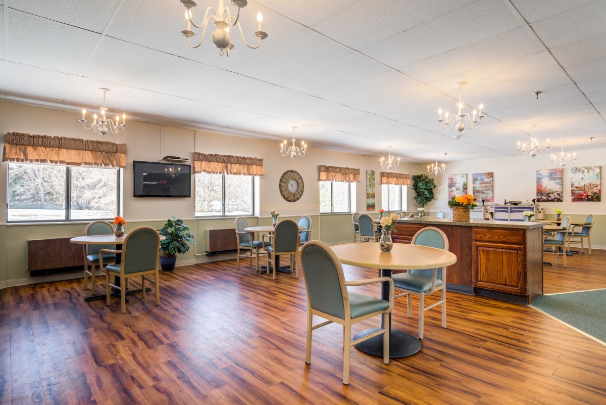 A spacious dining area with tables and chairs, featuring wood flooring and chandeliers.