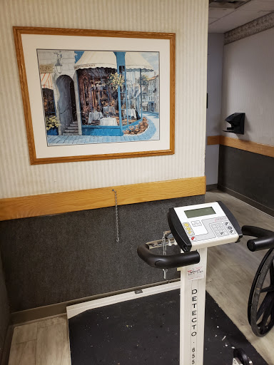 A stationary bike positioned in a healthcare facility, accompanied by an artwork on the wall.