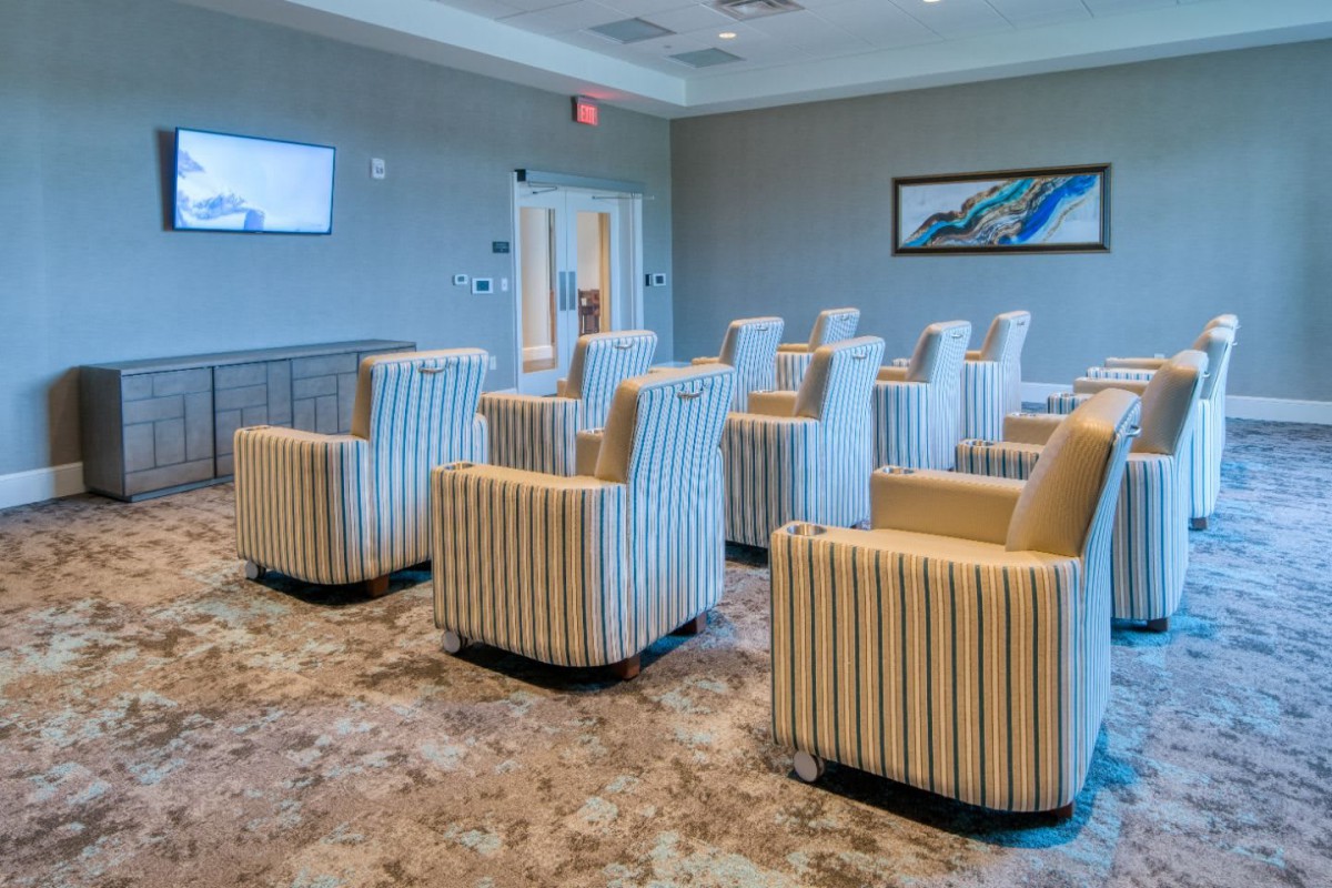 A modern lounge area featuring striped chairs and carpet flooring, arranged in a meeting room setting.