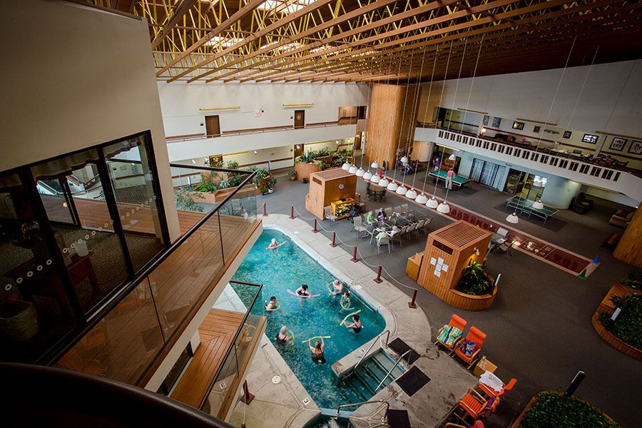A spacious indoor recreational center with people enjoying the pool area and relaxing in the spa.